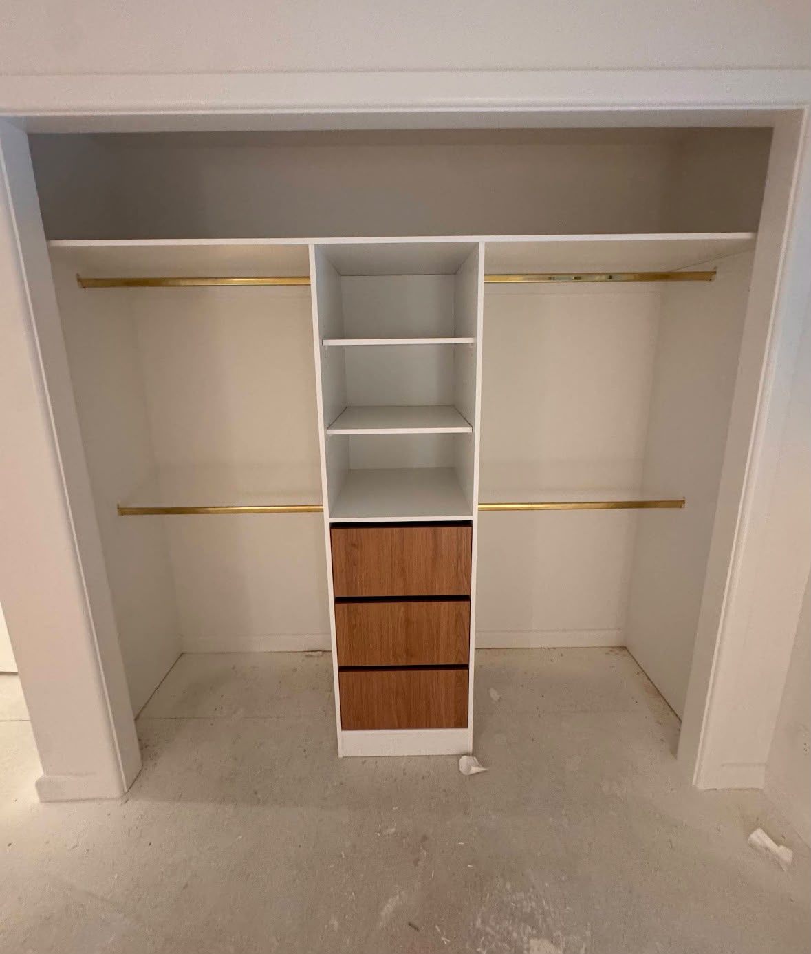 Built-in robe installed on a new-build site, with shelving tower, drawers and brass rails