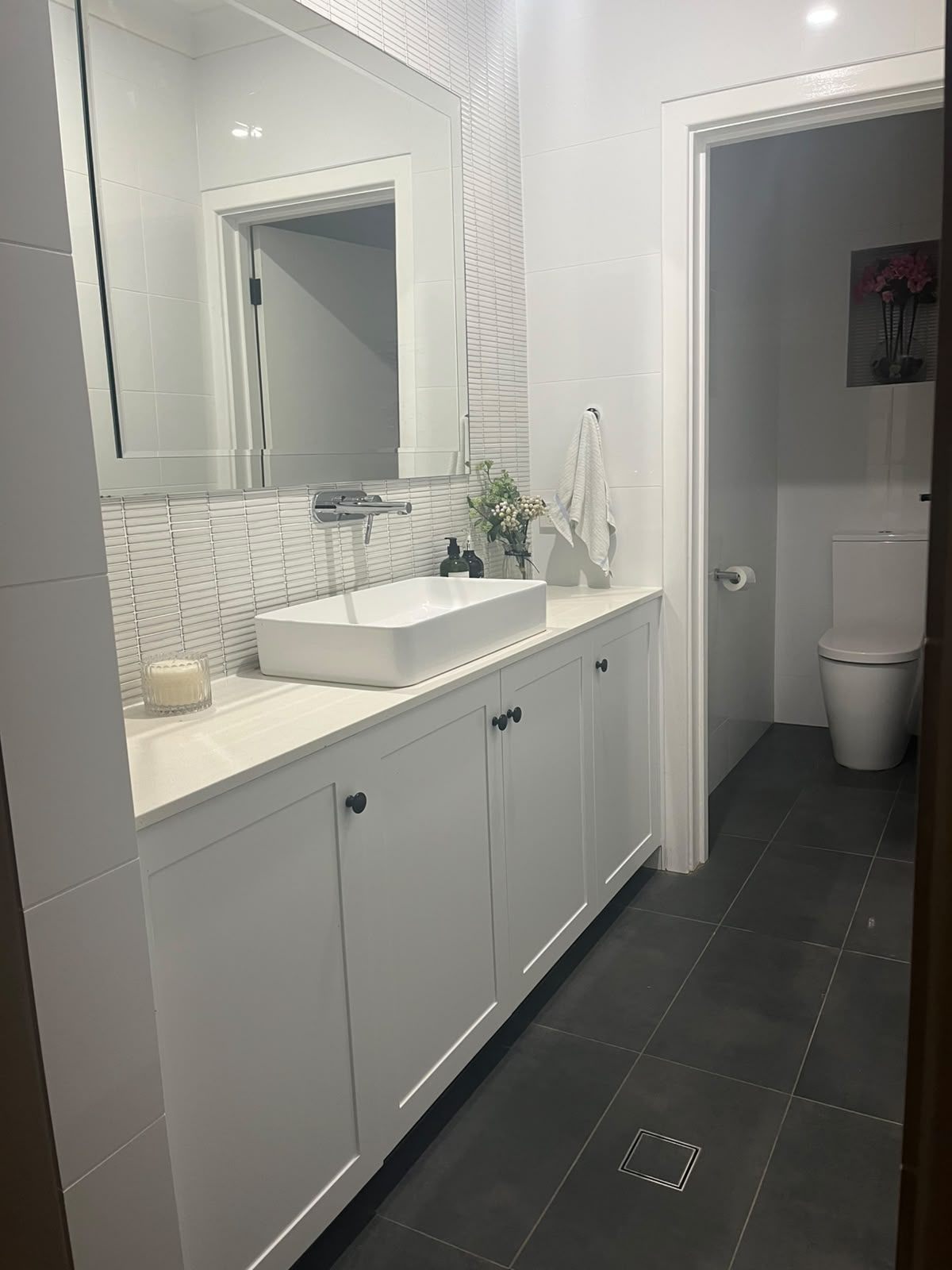 White shaker bathroom vanity with stone top and black knobs