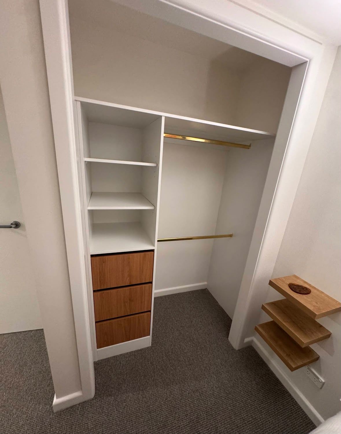 Walk-in robe with white shelving, timber-look drawers and brass hanging rails